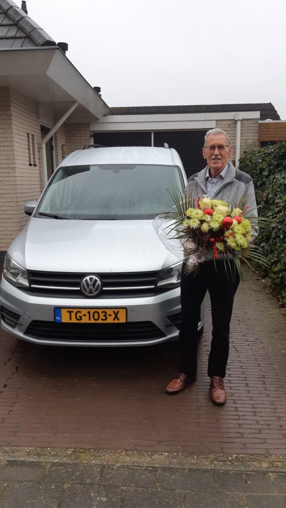 man met bloemen bij auto